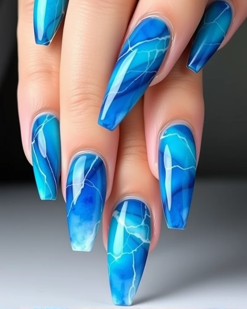 7 Dreamy Watercolor Nail Art Designs You Need to Try This Season 3 Long stiletto nails showcasing deep cerulean and turquoise watercolor pigments blended into intricate, ocean-inspired swirls.