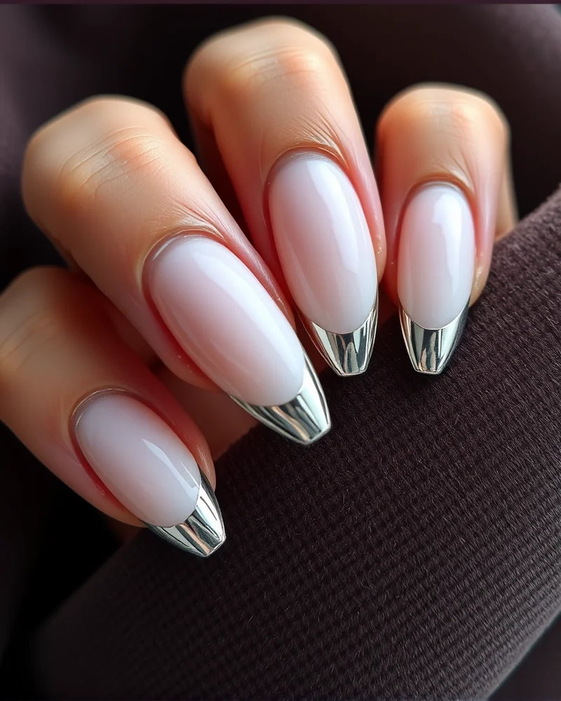 Almond-shaped nails showcasing a clean, milky white base with sharp, mirror-like silver chrome French tips.