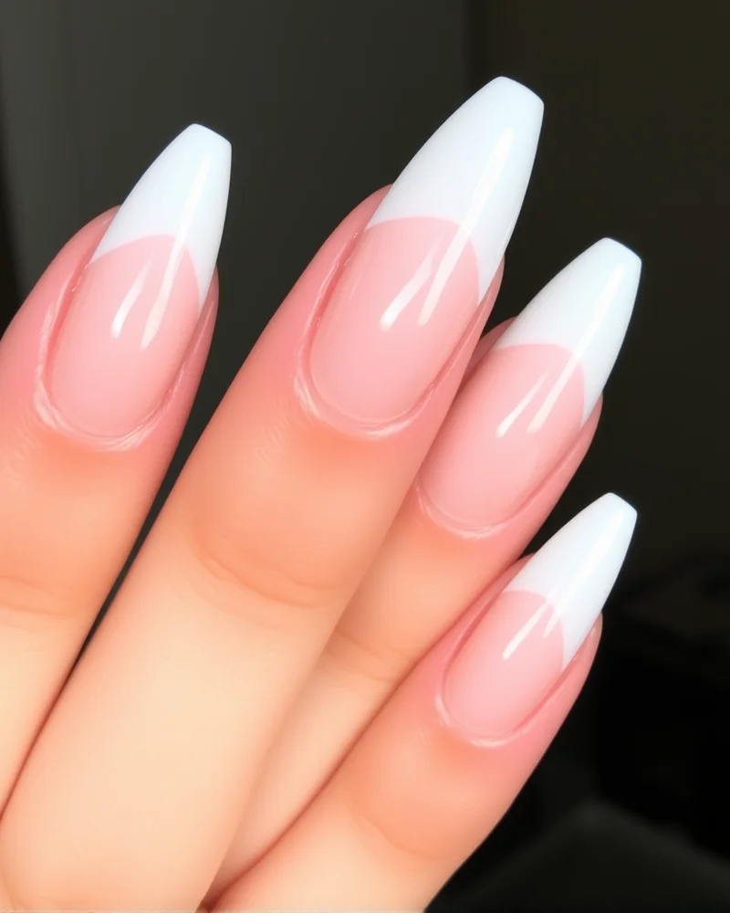 10 French Tip Nail Designs That Will Define Your Aesthetic This Year 7 Sharp stiletto-shaped nails with a V-shaped white French tip over a clear jelly base.
