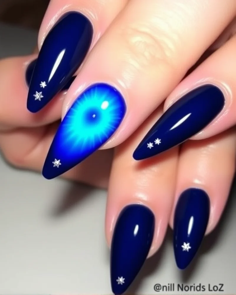 7 Viral Aura Nail Art Ideas That Will Elevate Your Manicure Game 3 Long stiletto nails with deep navy backgrounds and bright blue glowing center auras featuring delicate star accents.