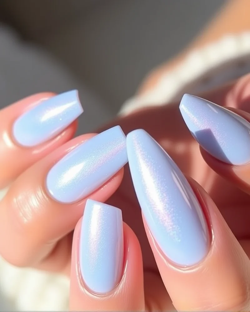 Long stiletto nails with a milky baby blue base and a shiny, iridescent glazed finish that captures soft light.