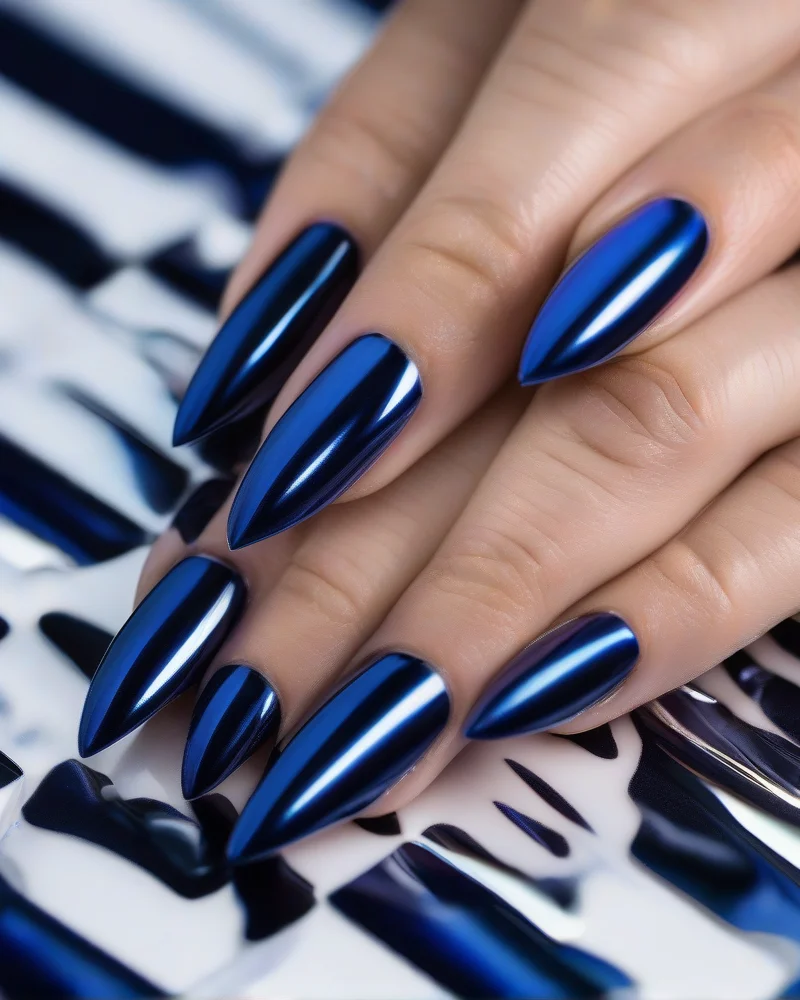 7 Subtle 4th of July Nails That Are Chic, Not Cheesy 5 Close-up of stiletto nails covered in a subtle navy blue chrome glaze with an iridescent shimmer.