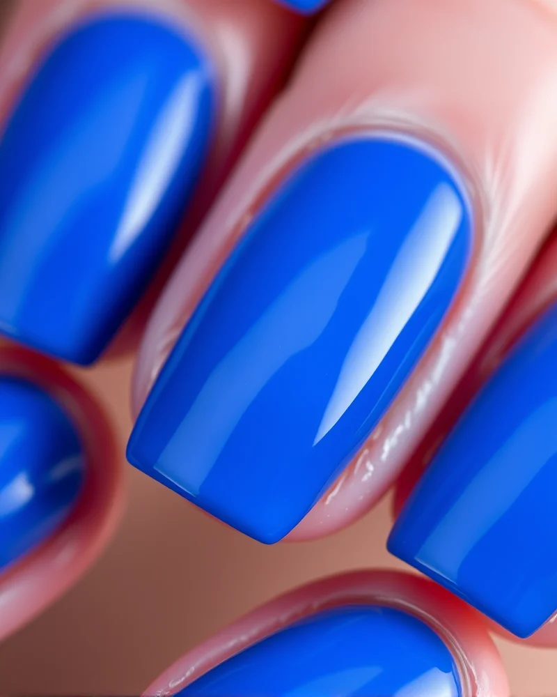 7 Viral July Nail Colors That Are Defining This Summer’s Aesthetic 2 High-gloss electric blue stiletto nails catching the light, featuring a vibrant, solid cobalt pigment that commands attention.