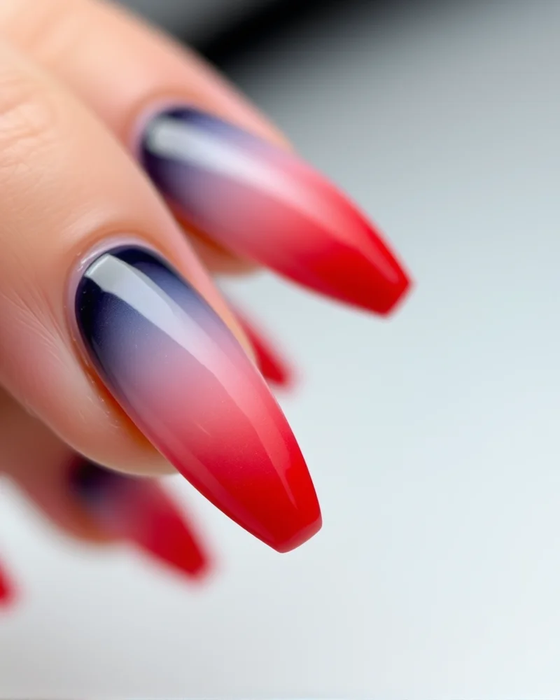 Coffin-shaped nails featuring a seamless blended ombré gradient from navy blue to white to bright red.