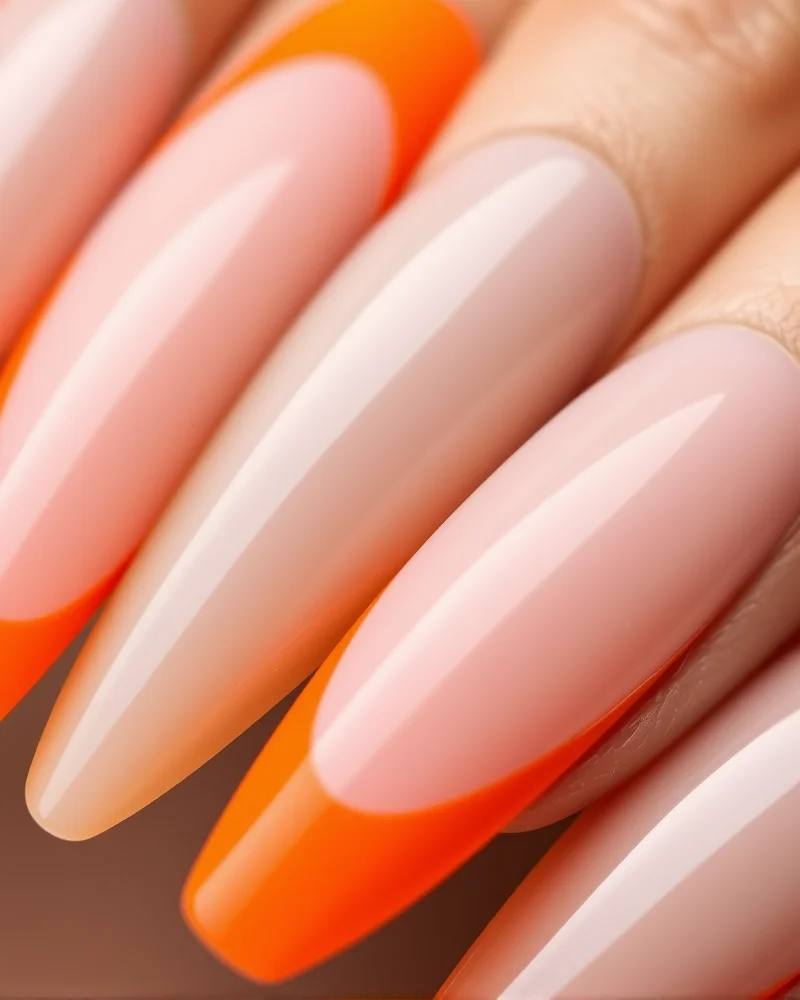 Stiletto-shaped nails with a nude, neutral base and razor-thin neon orange French tips, showcasing a modern and high-contrast look.