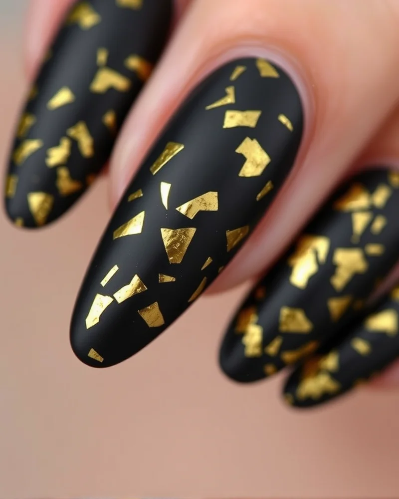 15 Chic September Nail Ideas to Transition Into Autumn 6 Matte black nails with gold leaf foil, dramatic September look.